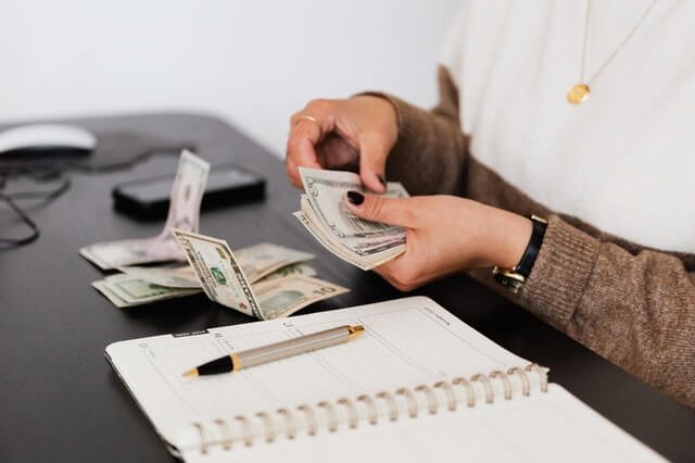 About crop payroll clerk counting money while sitting at table